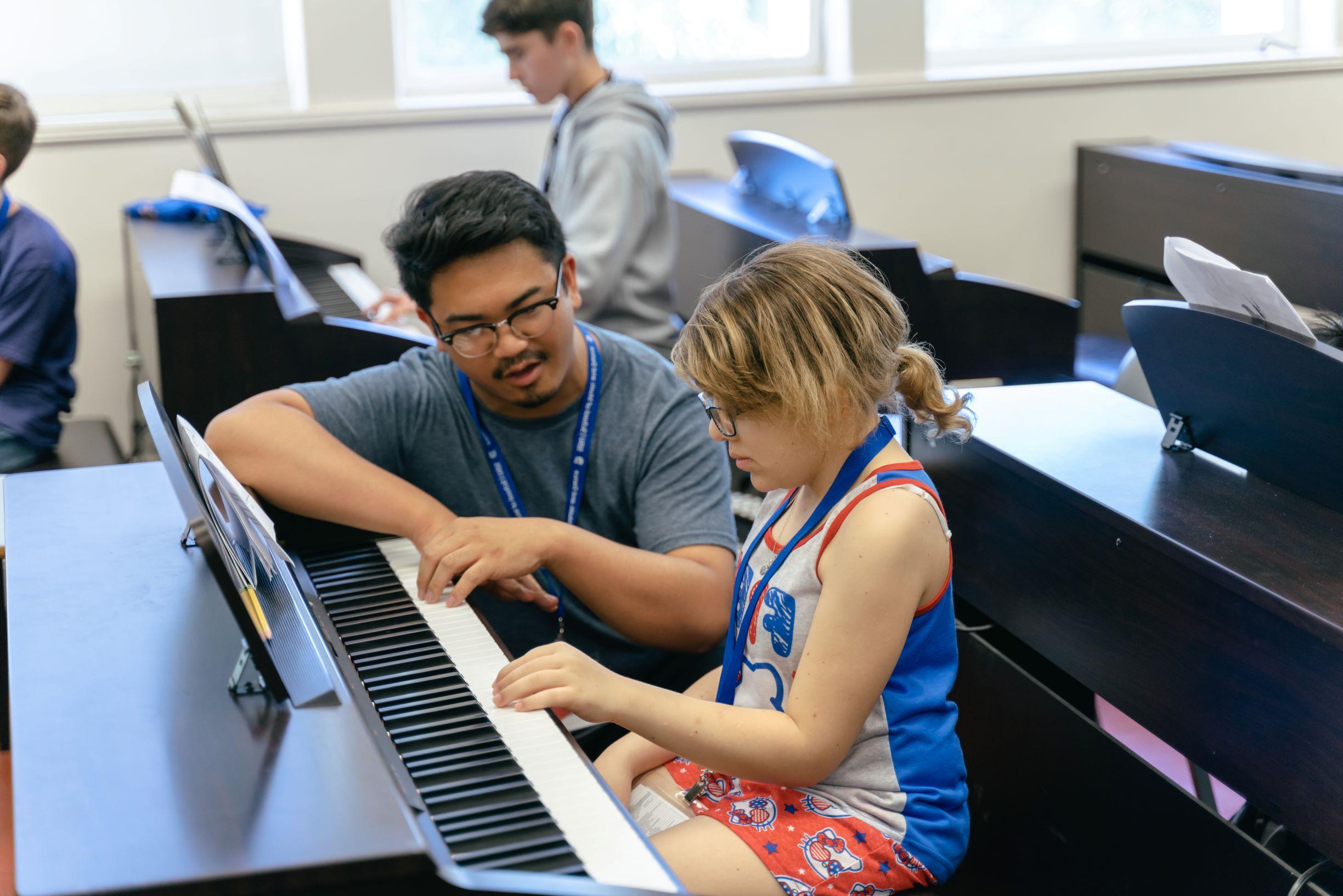 一位老师教一位年轻的学生如何弹奏键盘.